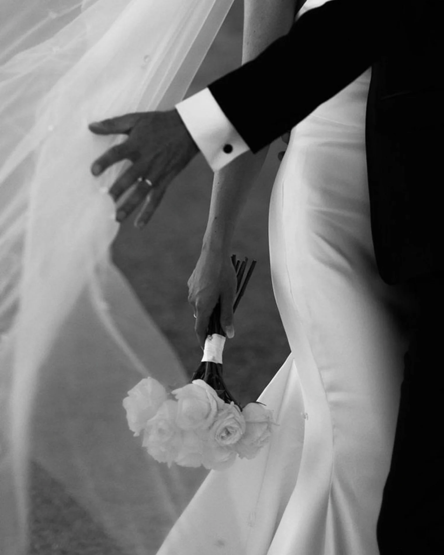 Las manos de los novios entre el velo y el ramo
