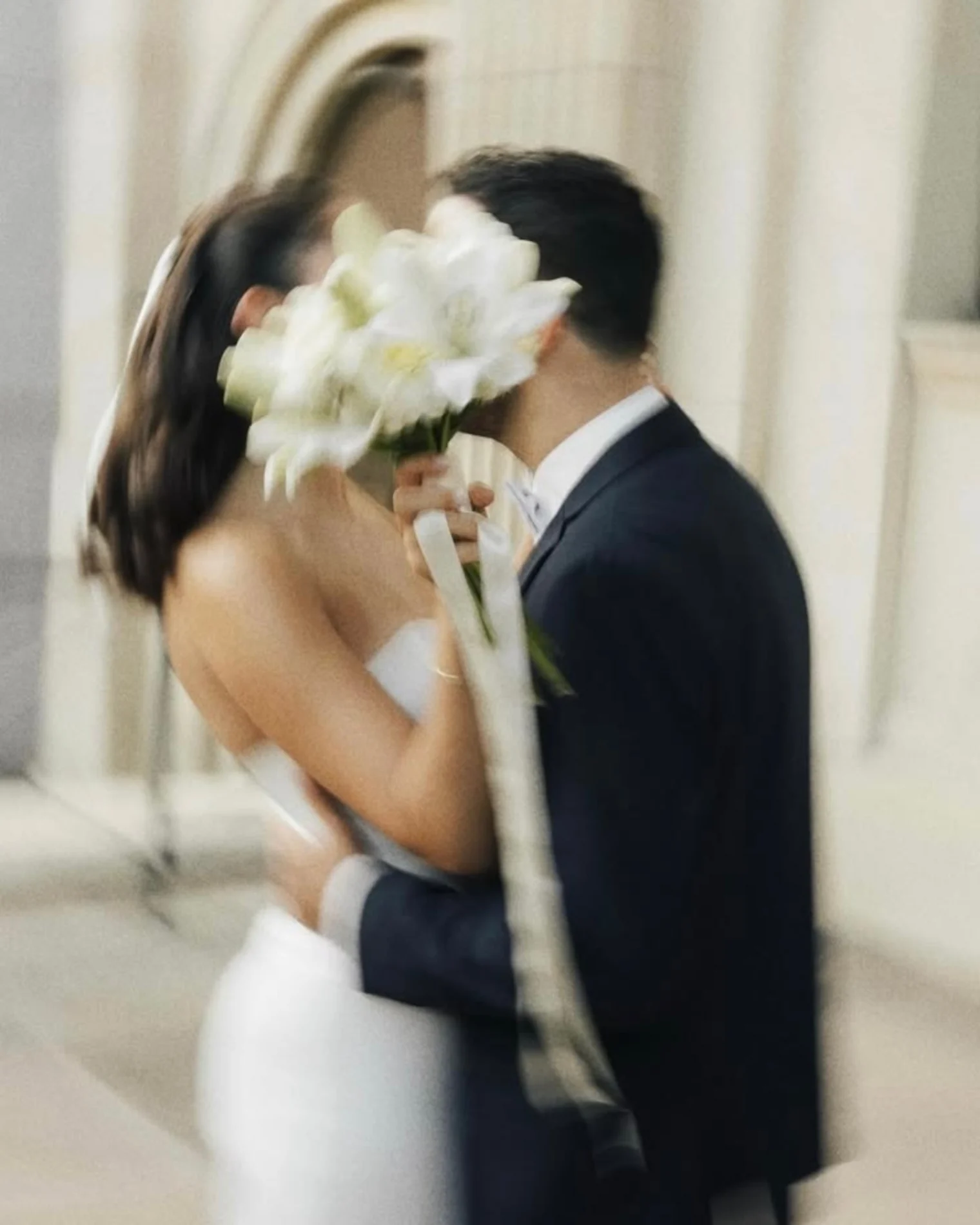 Un beso de los novios detrás de su ramo de flores